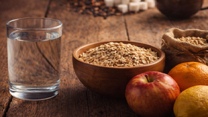 A simple earthen pot with water and natural herbs on a wooden table — representing simplicity, natural living, and generational health